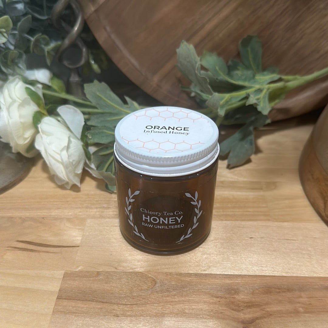 Chicory Tea Co'.s Orange Honey view from front on a wood floor with leaves and barrel in background.