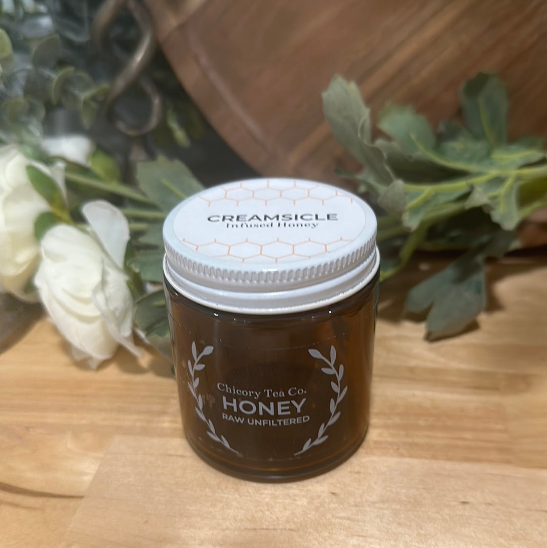 An artistic product photo of Chicory Tea Co.'s Creamsicle Honey in the jar, view from the front