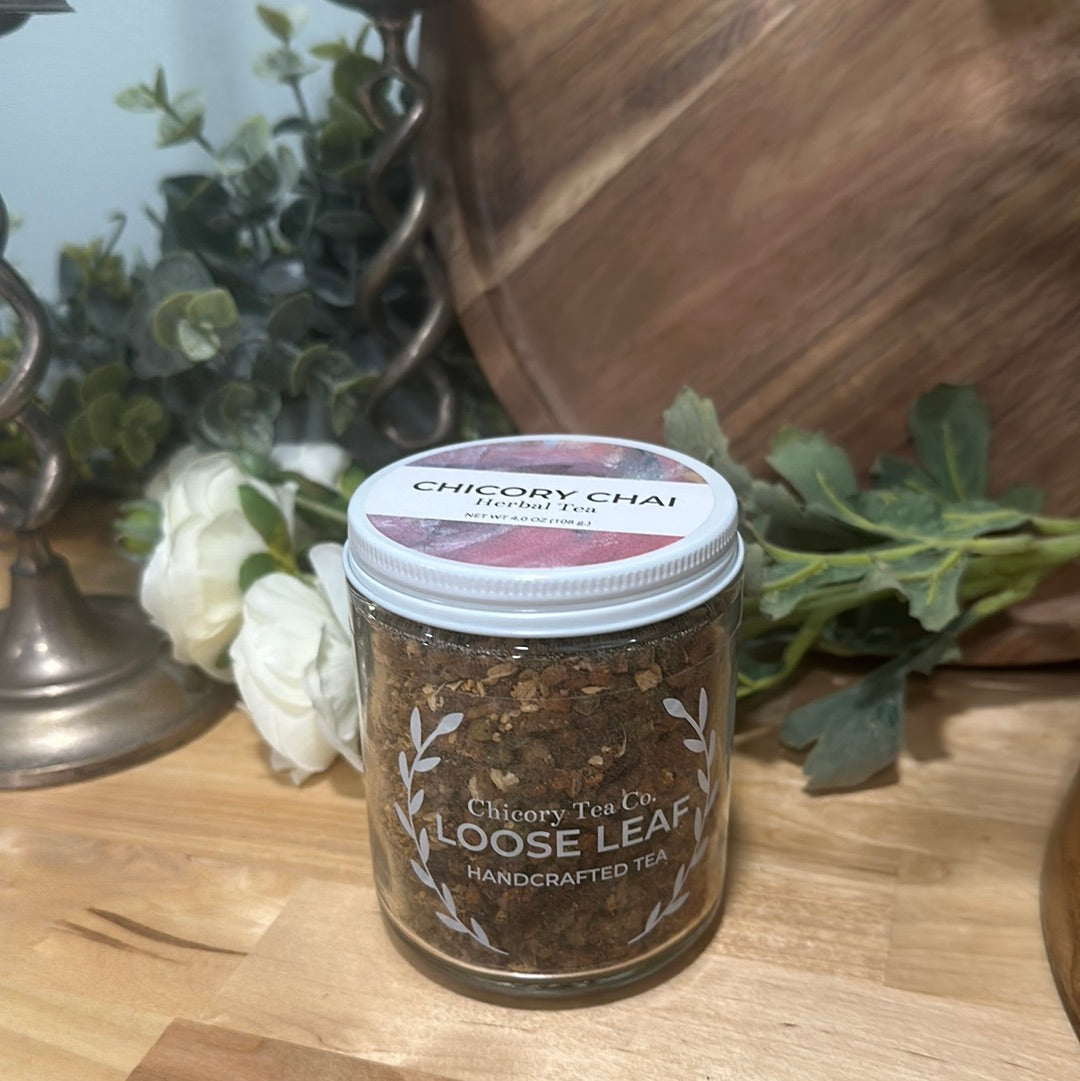 An artistic product photo of Chicory Tea Co.'s Chicory Chai Herbal Tea in the jar, view from the front with flowers and barrel in the background